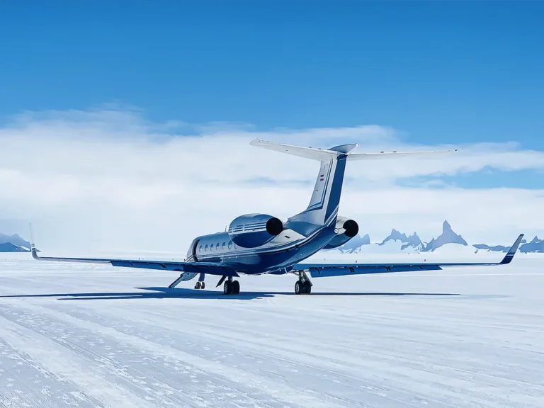 Business jet parked on a snowy runway under a clear blue sky in Antarctica, highlighting a unforgettable travel experience